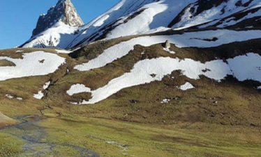 Snow at mountains and greenery at bottom with crystal clear water