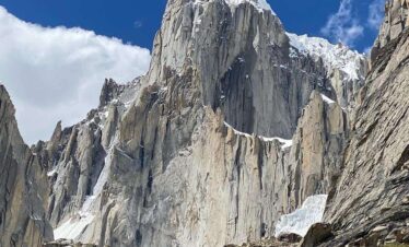 Trekkers walking through green alpine meadows on the trail to Nangma Valley near Skardu Baltistan.