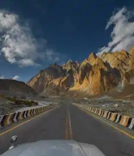 Scenic highway cutting through towering majestic mountains in Skardu, with narrow roads, rugged rock formations, and stunning natural beauty along the route
