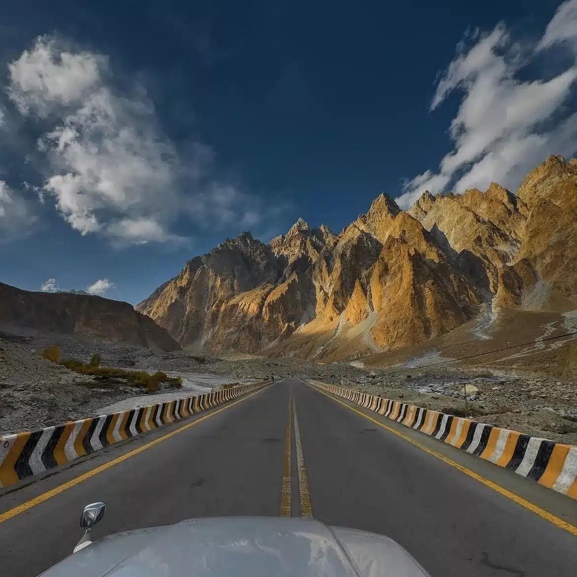 Scenic highway cutting through towering majestic mountains in Skardu, with narrow roads, rugged rock formations, and stunning natural beauty along the route